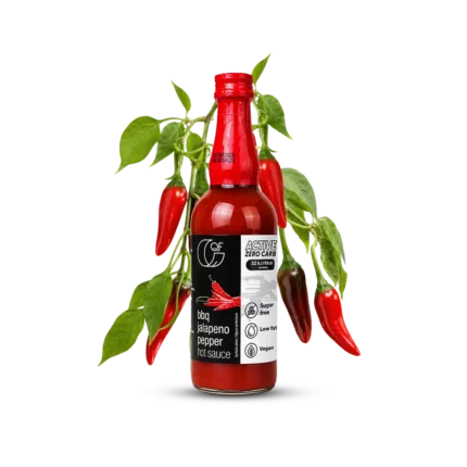 butelka sosu BBQ Jalapeno QF Active na tle gałązek z papryczkami Jalapeno