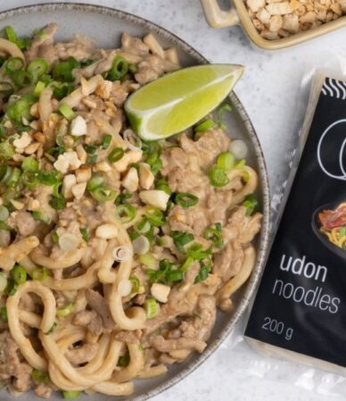 Talerz makaronu udon z mielonym indykiem w sosie orzechowym, obok limonka i opakowanie makaronu Udon QF Active