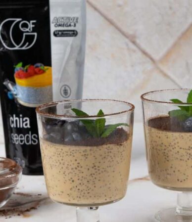Fit tiramisu z nasionami chia, kakao i borówkami w dwóch czarkach, podane obok miseczki z kakao oraz opakowania nasion chia Quality Food.